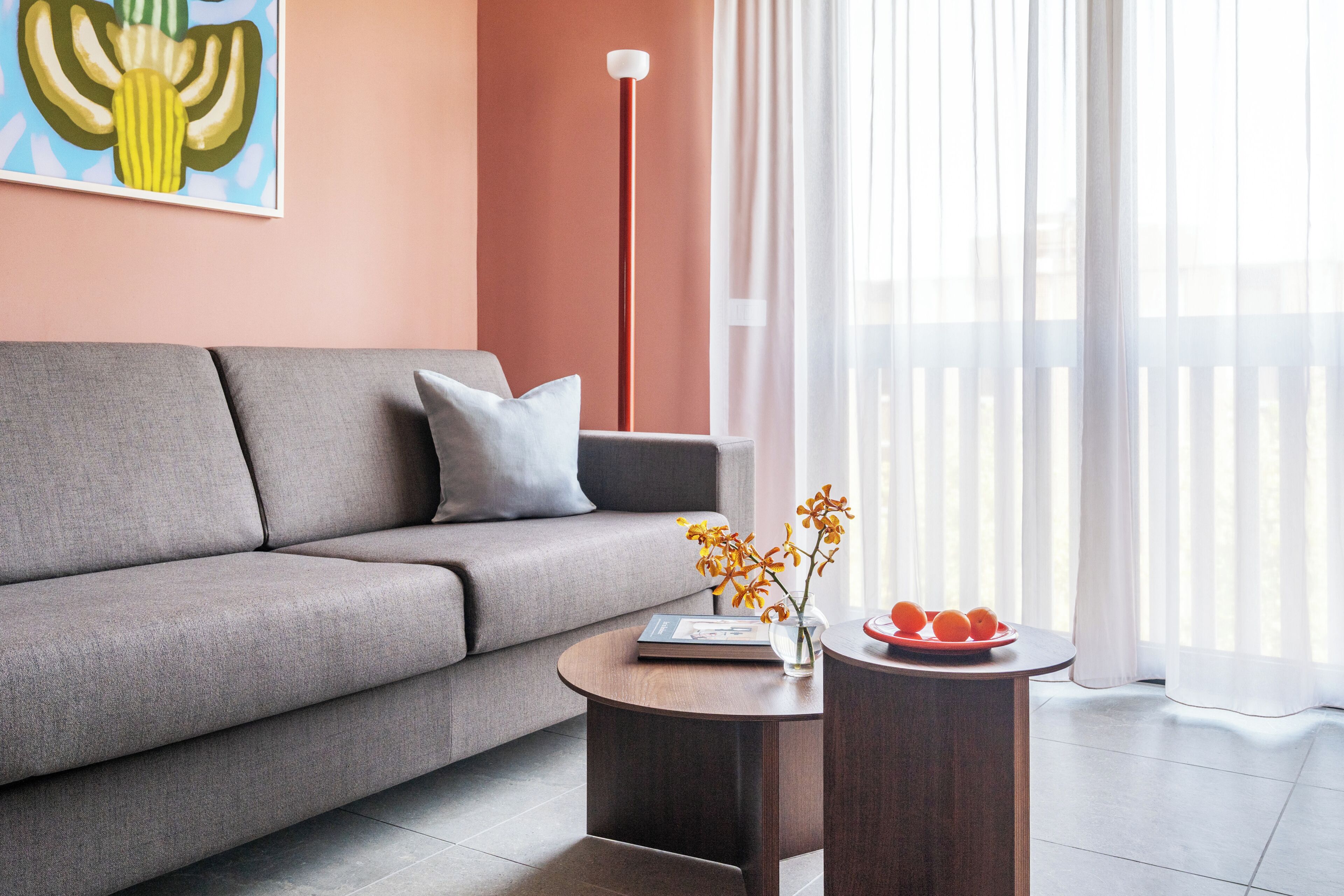 Un salon moderne avec un canapé gris, une table basse ronde et un lampadaire.