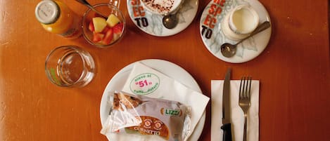 A table with a plate of food, a glass of juice, a cup of coffee, a fork, and a knife.
