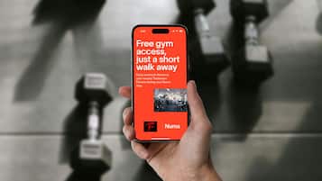 Eine Hand hält ein Smartphone, auf dem eine Fitness-App mit Informationen zu Trainingsmöglichkeiten angezeigt wird.