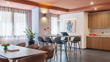 Un comedor moderno con una mesa y sillas de madera, un florero con flores y un portátil sobre la mesa.