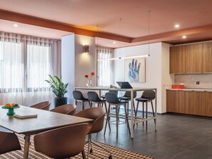 A modern dining area with a wooden table and chairs, a vase with flowers, and a laptop on the table. - Numa Rome Trastevere (Rome)