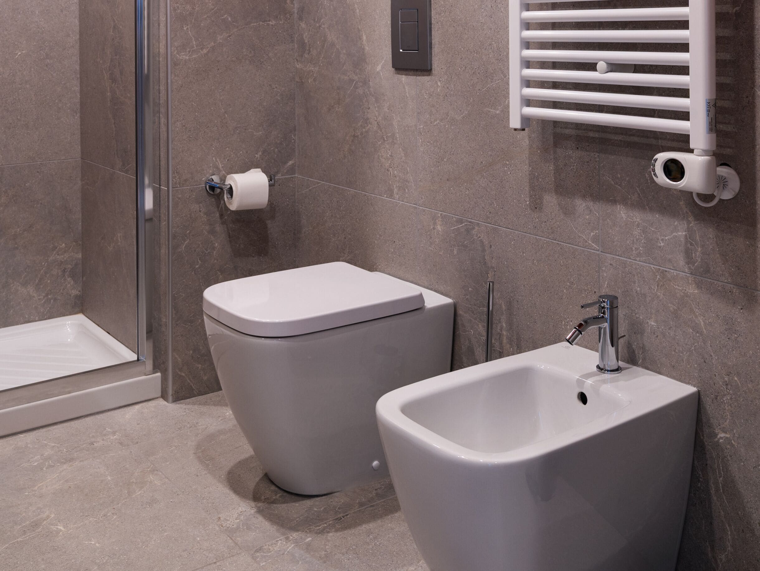 A modern bathroom with a toilet, bidet, and shower.