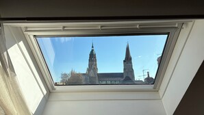 A skylight window with a view of a church with two spires. - Cathedral view apartment (Bayeux)