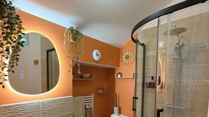 A modern bathroom with a round sink, toilet, and a glass-enclosed shower. - Cathedral view apartment (Bayeux)