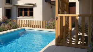 A residential property with a swimming pool, a wooden gate, and a tiled patio area.
