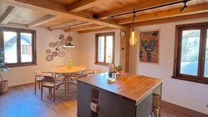 A spacious kitchen with a central island, wooden ceiling beams, and large windows.