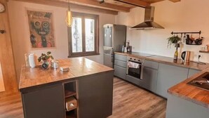 A modern kitchen with wooden beams, a central island, and a built-in oven.