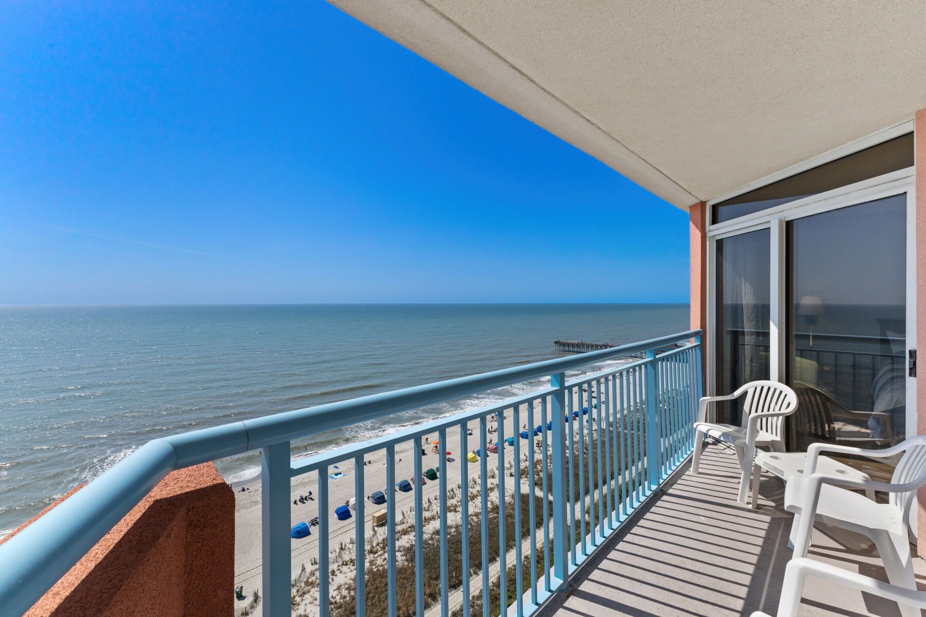 A balcony with a view of the beach and ocean.