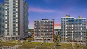 A high-rise hotel with multiple floors, a central courtyard with a pool, and a beach area with umbrellas.