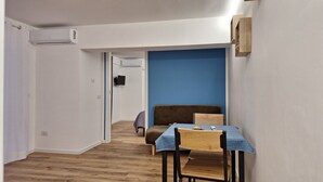 A narrow hallway with a wooden floor, a blue wall, a brown sofa, and a table with a blue tablecloth. - Charming 1-bedroom apartment in wonderful Palermo with AC, WiFi (Palermo)