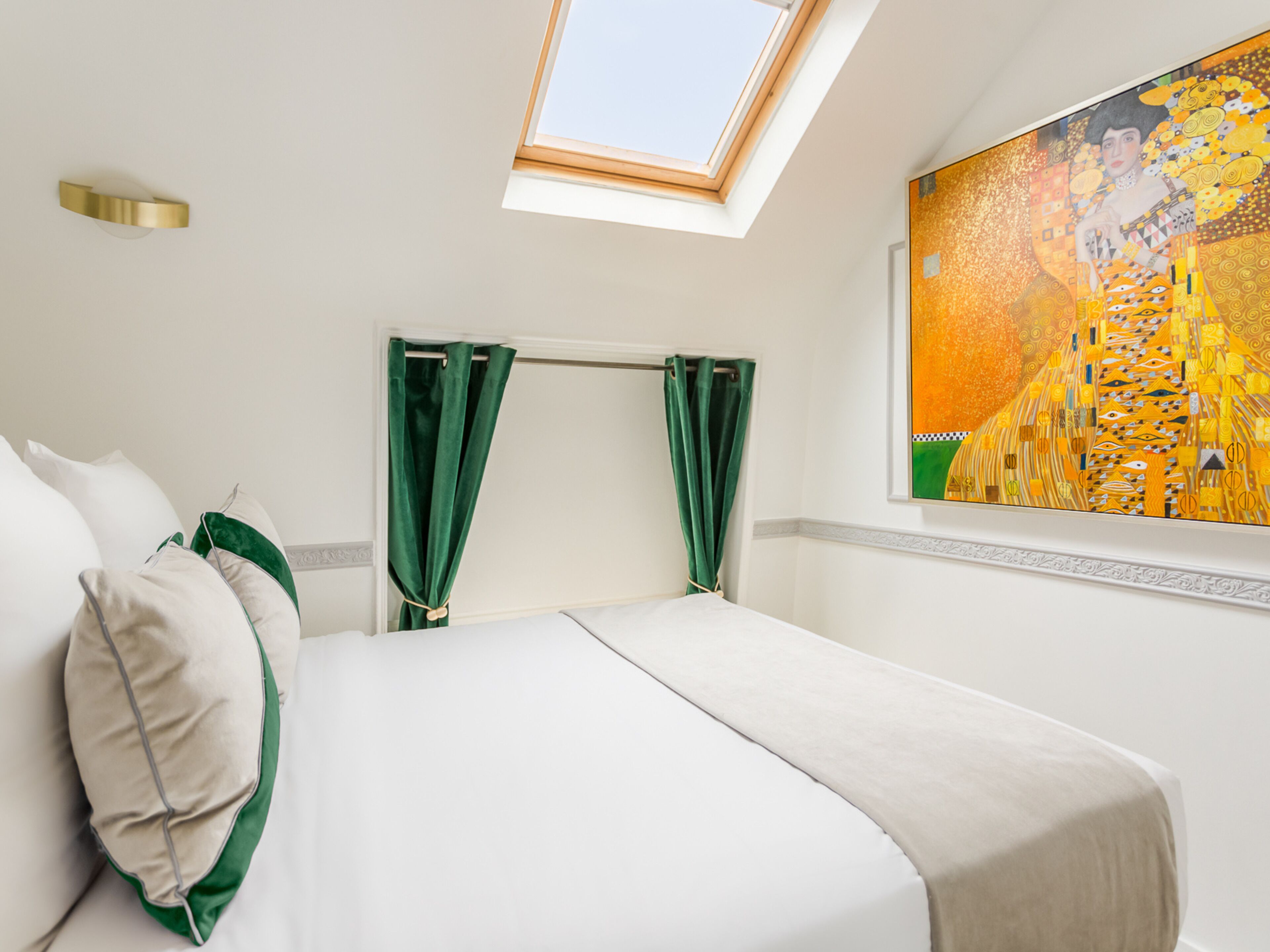 Ein Hotelzimmer mit Bett, grünen Vorhängen, einem Oberlicht und einem großen Gemälde an der Wand.