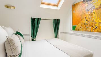 Ein Hotelzimmer mit Bett, grünen Vorhängen, einem Oberlicht und einem großen Gemälde an der Wand.