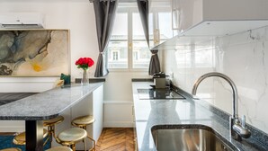 Een moderne keuken met een marmeren aanrechtblad, een roestvrijstalen spoelbak en een visgraat parketvloer.