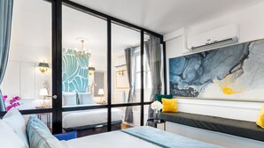 Een moderne hotelkamer met een groot bed, een zithoek met uitzicht en een groot abstract schilderij aan de muur.