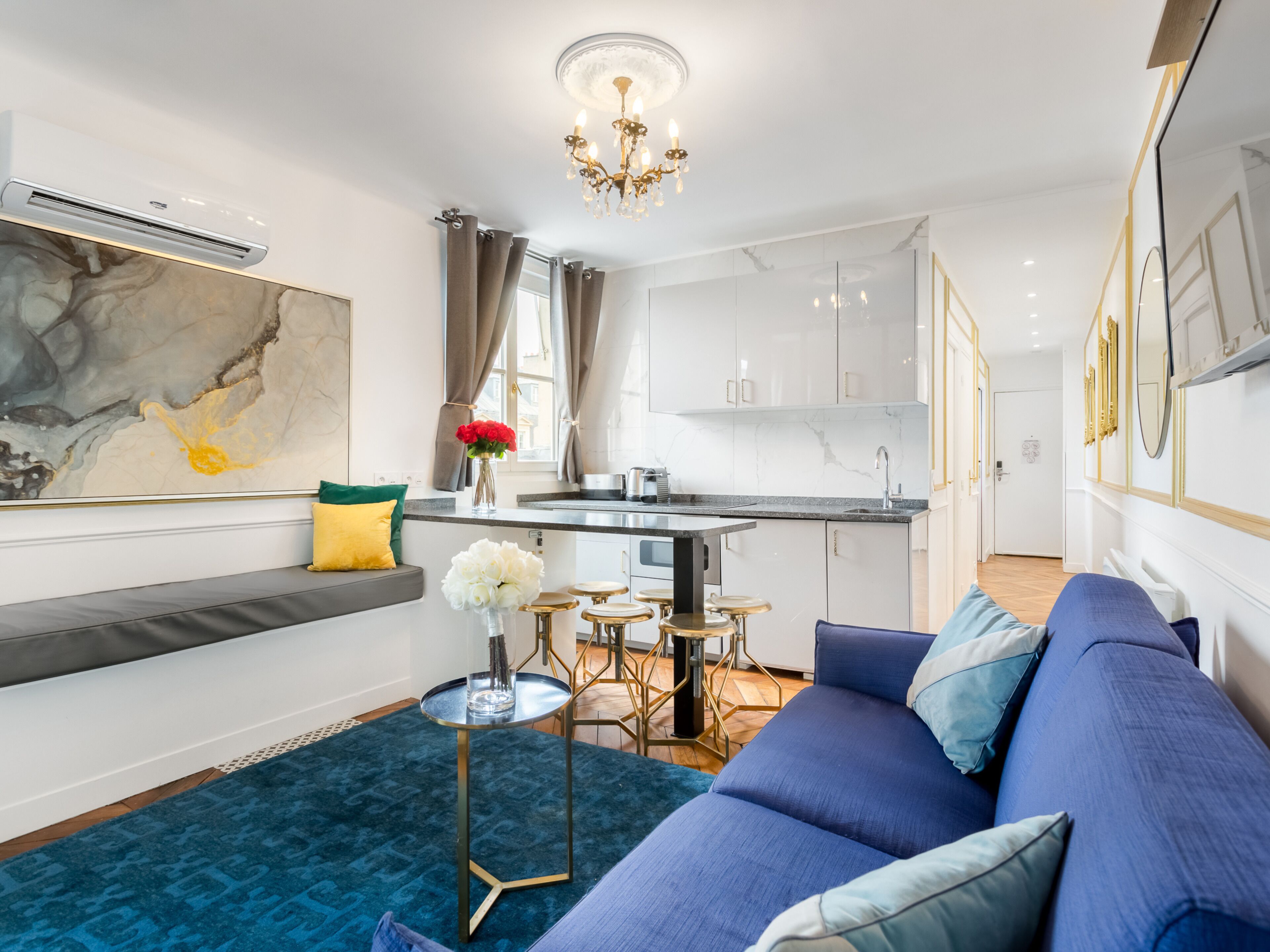 A modern living room with a blue sofa, a small round table, and a large abstract painting on the wall.