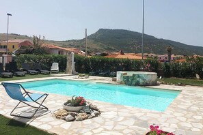 A swimming pool with lounge chairs, a hot tub, and a mountainous backdrop. - Residenze Turistiche della Ciaccia (Valledoria)