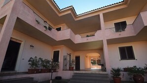 A multi-level building with balconies, potted plants, and a central staircase. - Residenze Turistiche della Ciaccia (Valledoria)
