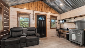 A log cabin interior with a leather sofa, a kitchen area, and a wooden ceiling. - Broken Arrow - Private Escape, Hot Tub & Fire Pit (Fredericksburg)