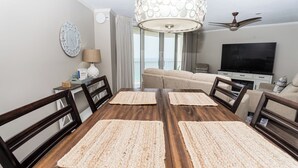 Ein Essbereich mit einem Holztisch, vier Stühlen, einer Uhr, einer Lampe und einem Fernseher im Hintergrund.