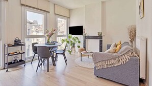 Un salon moderne avec une table à manger ronde, un canapé gris et une cheminée.