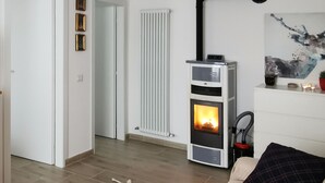 A living room with a sofa, a rug, a fireplace, a radiator, and a door. - Casa Polsa "1964" - #02
Holiday Home in the mountains (Polsa)