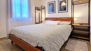 A bedroom with a bed, a wooden headboard, a nightstand, a lamp, a framed picture, a window with curtains, and a wooden floor. - Casa Polsa "1964" - #02
Holiday Home in the mountains (Polsa)