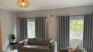 En moderne stue med en grå sofa, et sofabord og en potteplante.