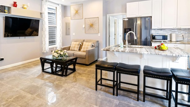 A modern kitchen with white cabinets, a stainless steel refrigerator, and a marble countertop.