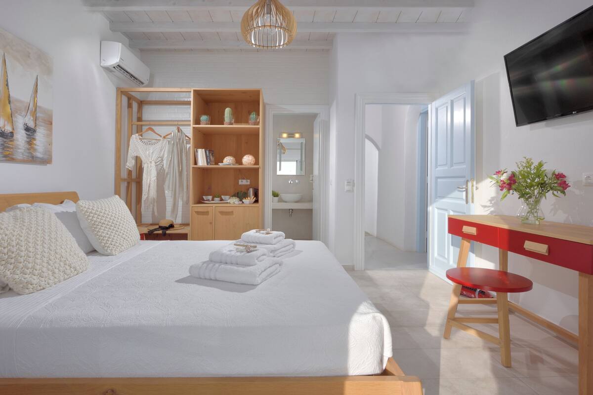 A bedroom with a bed, a wardrobe, a desk, and a TV.