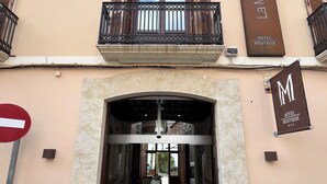 L’entrée d’un hôtel, avec un sol carrelé, un comptoir d’accueil et un balcon doté de volets en bois.