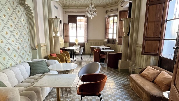 Une pièce spacieuse avec un sol à motifs, un canapé, une table à manger et un lustre.