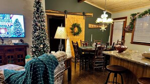Una sala de estar acogedora con chimenea, un árbol de Navidad y un comedor con sillas y mesa de madera.