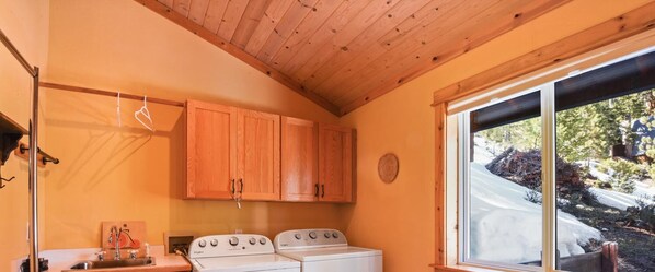 Una cocina con armarios de madera, estufa y ventana con vista a terreno cubierto de nieve.
