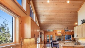 A spacious kitchen with wooden cabinetry, a granite countertop, and a dining area with a table and chairs.