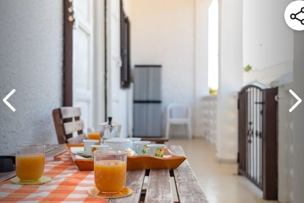 A breakfast table with orange juice glasses and a tray of food, set in a bright room with a checkered tablecloth.