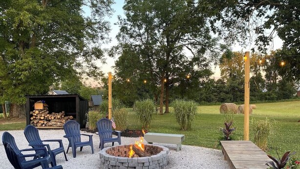 Un espacio al aire libre con una chimenea, sillas y un banco.