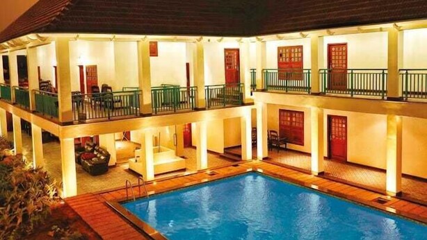 A hotel with a swimming pool, multiple balconies, and a warm, inviting atmosphere. - Napier Heritage (Kochi)