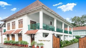 A two-story building with a white facade, green railings, and a wooden gate labeled "Napier Heritage". - Napier Heritage (Kochi)