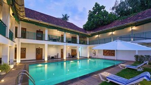 A hotel with a swimming pool, outdoor seating, and a covered patio area. - Napier Heritage (Kochi)