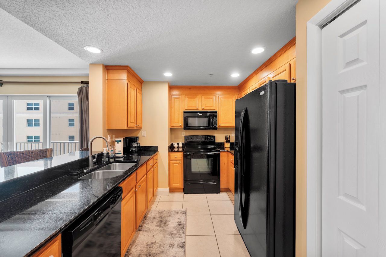 A modern kitchen with wooden cabinets, a black refrigerator, and a black stove.