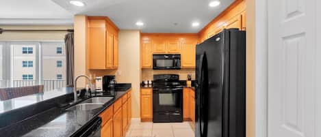 A modern kitchen with wooden cabinets, a black refrigerator, and a black stove.