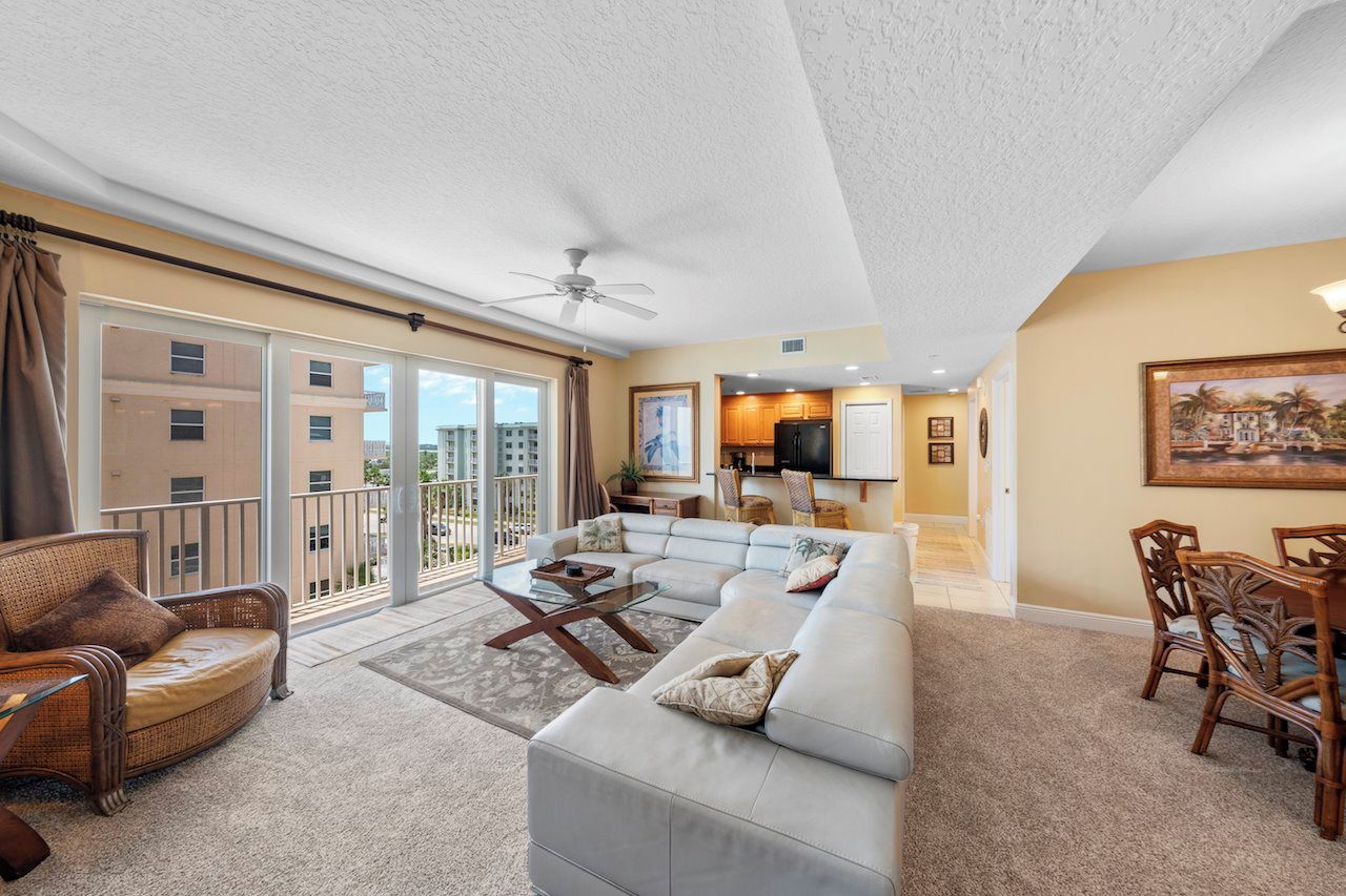 A spacious living room with a large sofa, a coffee table, and a dining area with wooden chairs.