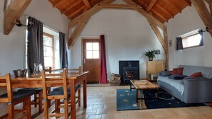 Ein gemütliches Wohnzimmer mit Holzesstisch, Stühlen, einer Couch und einem Kamin.