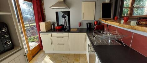 A compact kitchen with a stove, sink, and a window with a view of the outdoors.