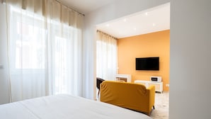 Ein Hotelzimmer mit einem großen Bett, einem gelben Sessel, einem Fernseher und einem kleinen weißen Schrank.