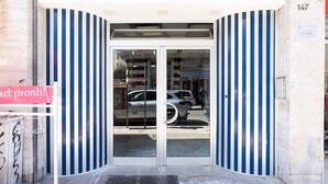 Ein Gebäudeeingang mit Glastür und gestreiften Wänden.