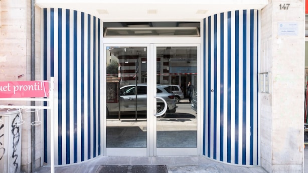 Entrada de un edificio con puerta de cristal y paredes a rayas.