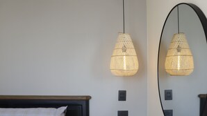 Un dormitorio con cama, mesita de noche y un espejo fijado a la pared.