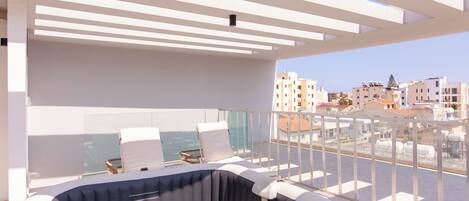 Terraço no topo do prédio com banheira de hidromassagem, espreguiçadeiras e vista para a paisagem urbana.