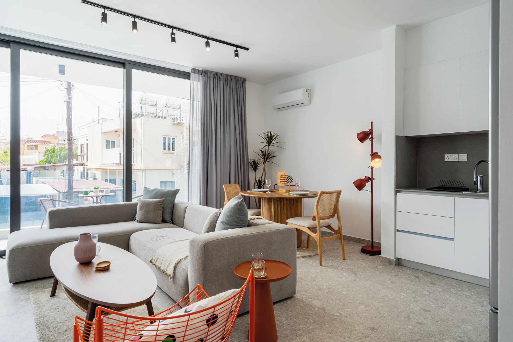 A modern living room with a sofa, a dining table, and a kitchen area.
